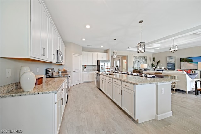 kitchen featuring stainless steel appliances, an island with sink, white cabinets, light stone counters, and decorative light fixtures