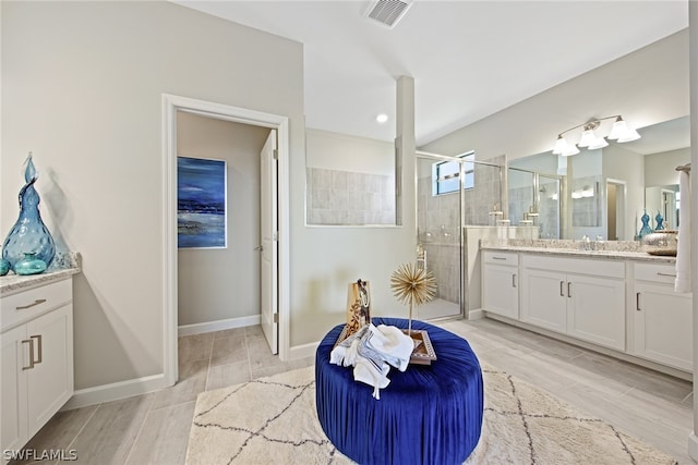 bathroom featuring a shower with shower door and large vanity