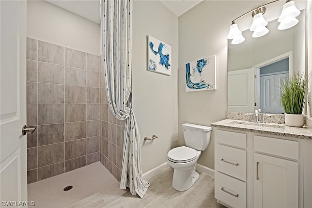 bathroom with tile floors, tiled shower, toilet, and vanity