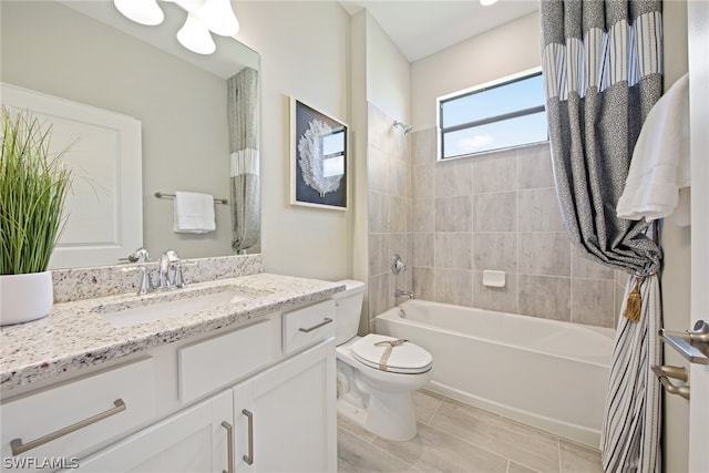 full bathroom with tile flooring, tiled shower / bath combo, toilet, and vanity with extensive cabinet space