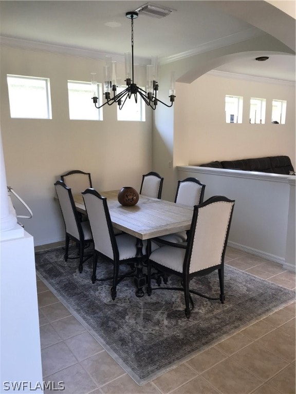 dining area with a healthy amount of sunlight, an inviting chandelier, tile floors, and crown molding