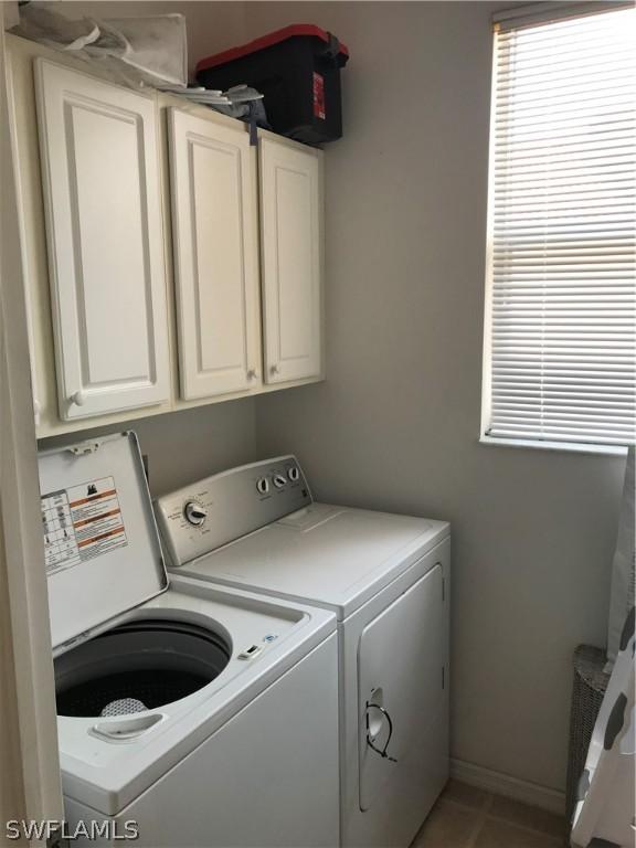 laundry area featuring cabinet space, tile patterned floors, baseboards, and washer and clothes dryer