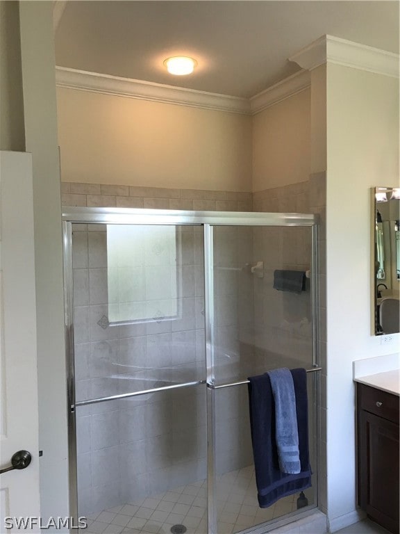 bathroom featuring walk in shower, ornamental molding, and vanity