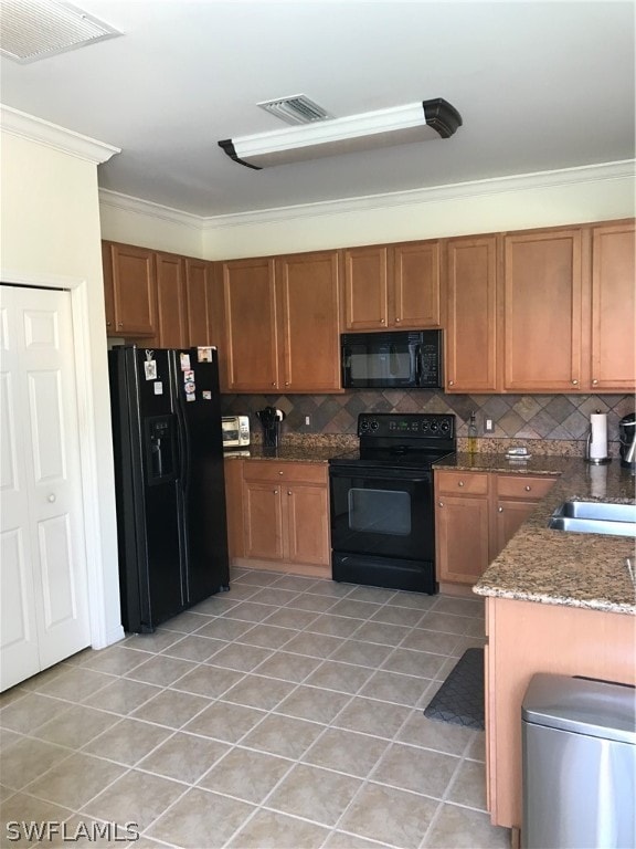 kitchen with dark stone countertops, black appliances, backsplash, sink, and light tile flooring