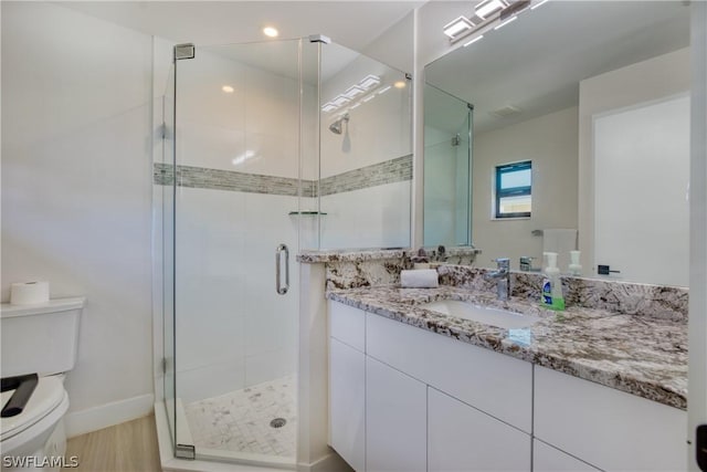 bathroom with vanity, wood-type flooring, a shower with shower door, and toilet