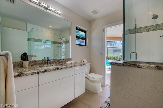 bathroom featuring vanity, toilet, and a shower with shower door