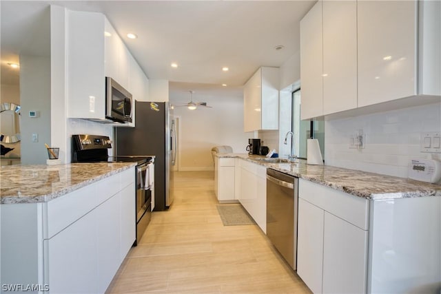 kitchen with white cabinetry, decorative backsplash, ceiling fan, stainless steel appliances, and light stone countertops