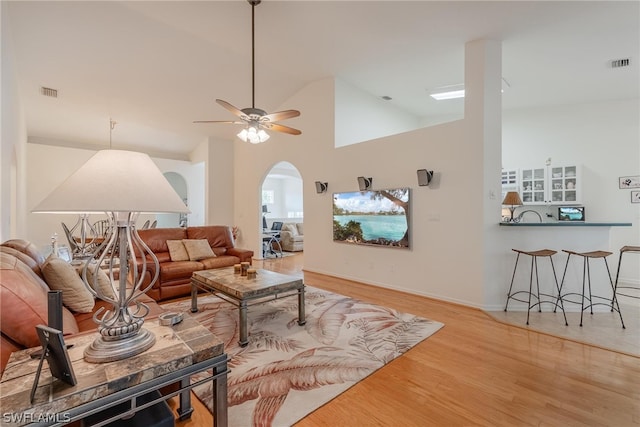 living room featuring high vaulted ceiling, ceiling fan, and light wood-type flooring