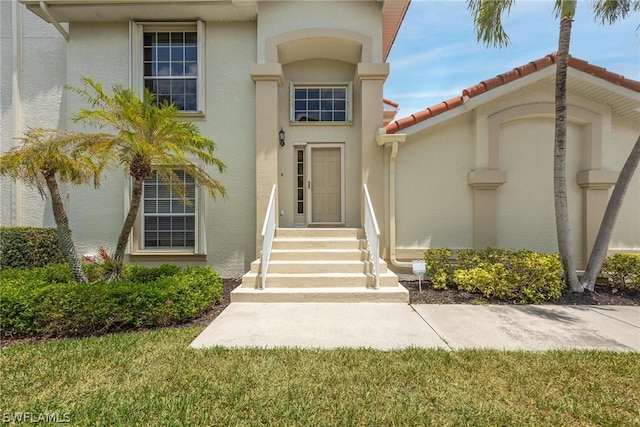 view of exterior entry featuring a lawn