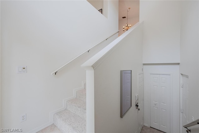 stairway with a high ceiling and an inviting chandelier