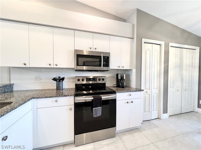 kitchen featuring backsplash, stainless steel appliances, vaulted ceiling, light tile patterned floors, and white cabinetry