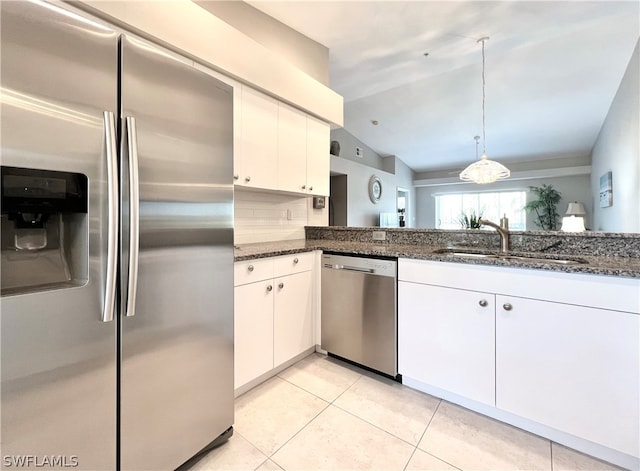 kitchen featuring white cabinetry, sink, stainless steel appliances, dark stone counters, and vaulted ceiling