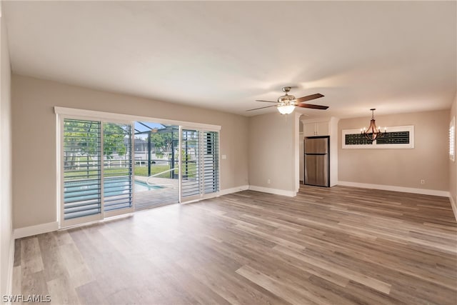 interior space featuring ceiling fan with notable chandelier and hardwood / wood-style floors