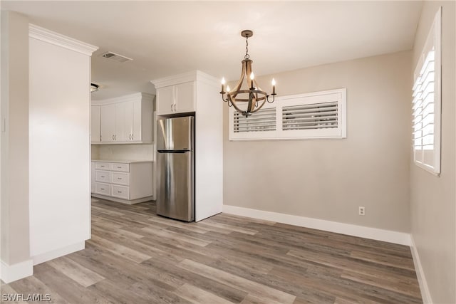 unfurnished dining area with light hardwood / wood-style flooring, a wealth of natural light, and an inviting chandelier