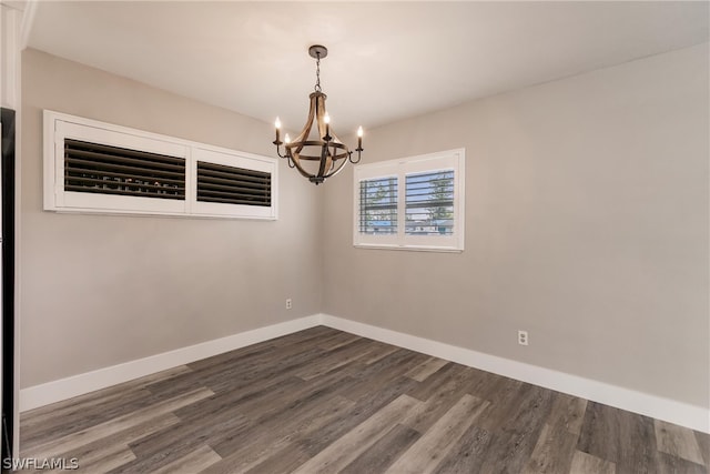 empty room with a chandelier and dark hardwood / wood-style floors