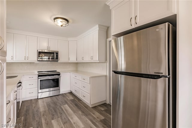 kitchen with appliances with stainless steel finishes, white cabinetry, backsplash, and hardwood / wood-style floors