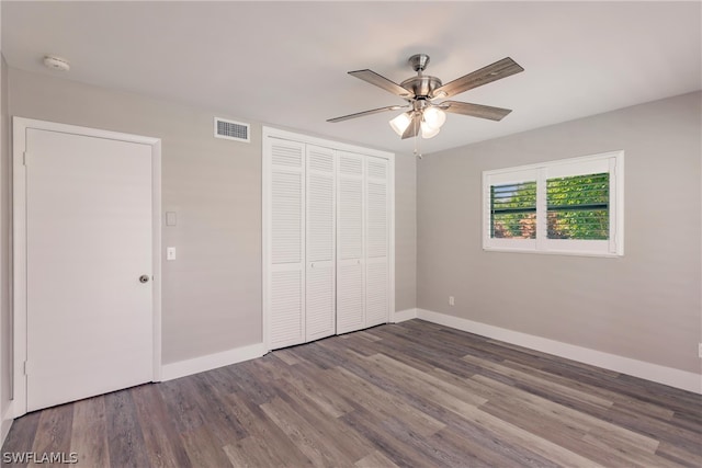 unfurnished bedroom with ceiling fan, a closet, and dark wood-type flooring