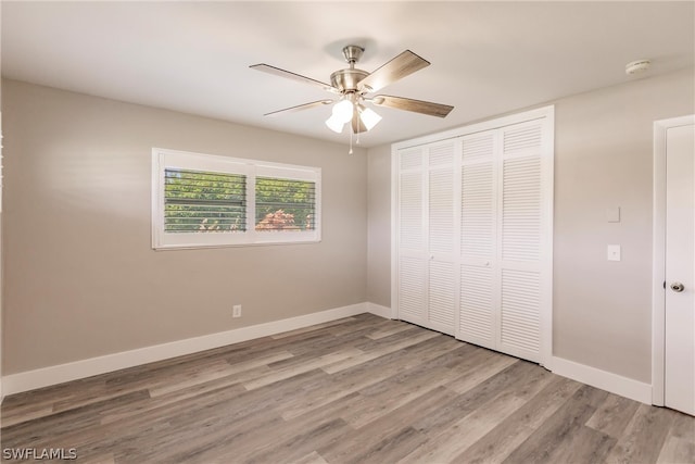 unfurnished bedroom featuring hardwood / wood-style floors, a closet, and ceiling fan