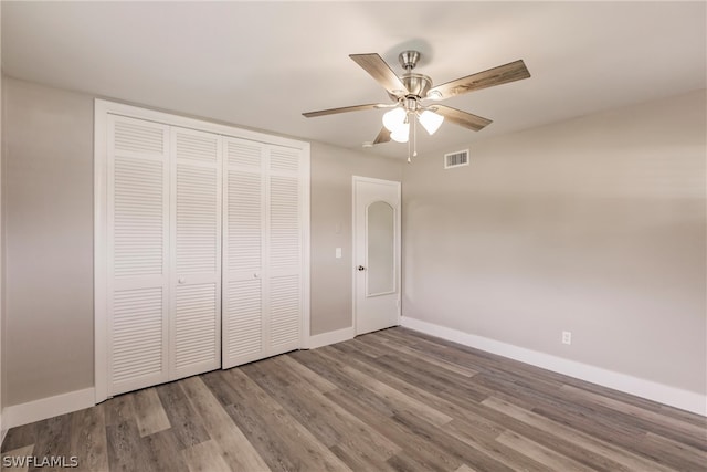 unfurnished bedroom with ceiling fan, a closet, and hardwood / wood-style floors