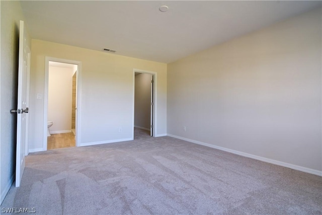 unfurnished bedroom featuring ensuite bath and light colored carpet