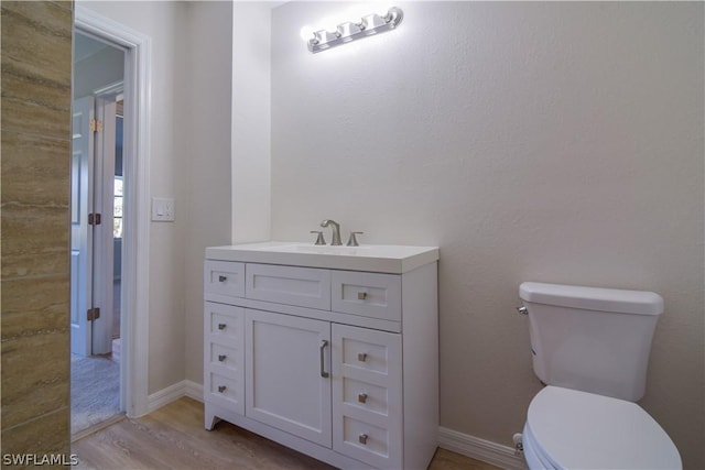 bathroom featuring wood-type flooring, toilet, and vanity