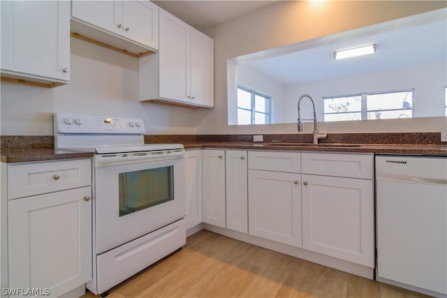 kitchen featuring white appliances, white cabinetry, dark stone countertops, sink, and light wood-type flooring