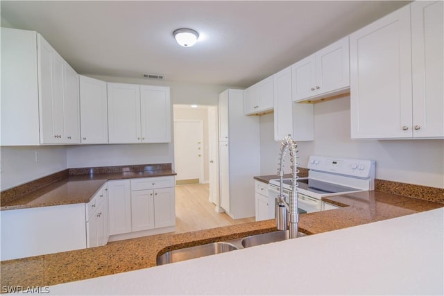 kitchen with light hardwood / wood-style floors, electric stove, and white cabinetry