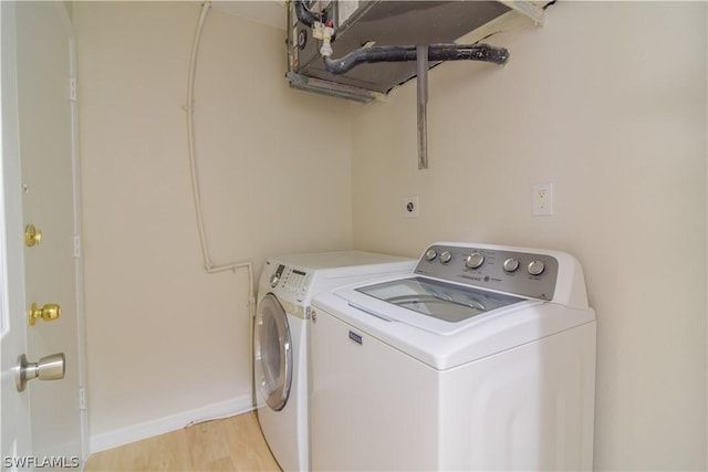 clothes washing area with light wood-type flooring and washing machine and clothes dryer