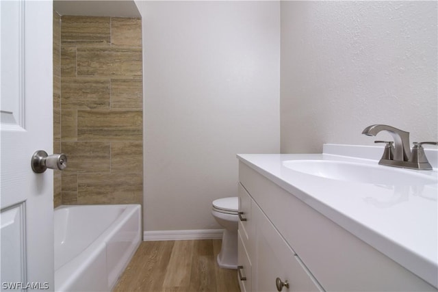 bathroom featuring toilet, a tub, hardwood / wood-style floors, and vanity