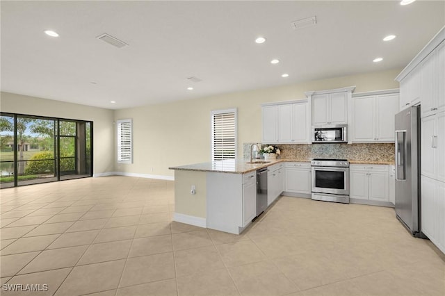 11643 Meadowrun Cir, Fort Myers, FL 33913 - kitchen with appliances with stainless steel finishes, a peninsula, backsplash, white cabinets, and recessed lighting
