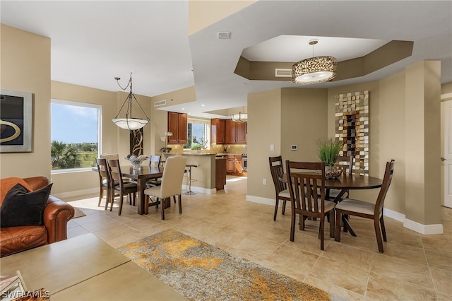 tiled dining room featuring a tray ceiling and a chandelier