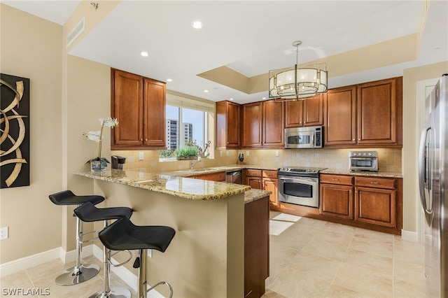 kitchen featuring decorative light fixtures, stainless steel appliances, kitchen peninsula, and tasteful backsplash