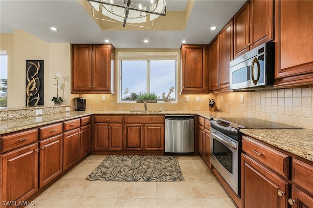 kitchen featuring light stone countertops, appliances with stainless steel finishes, sink, tasteful backsplash, and light tile flooring