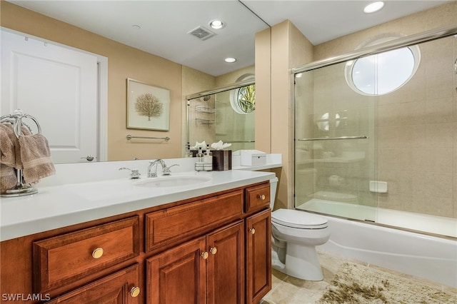 full bathroom featuring a wealth of natural light, combined bath / shower with glass door, toilet, and large vanity