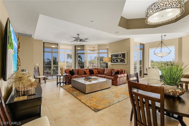 living room with floor to ceiling windows, a tray ceiling, ceiling fan, and light tile floors