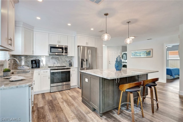 kitchen with white cabinets, a center island, stainless steel appliances, and sink