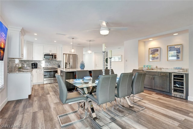 dining area featuring light hardwood / wood-style flooring, ceiling fan, beverage cooler, and sink