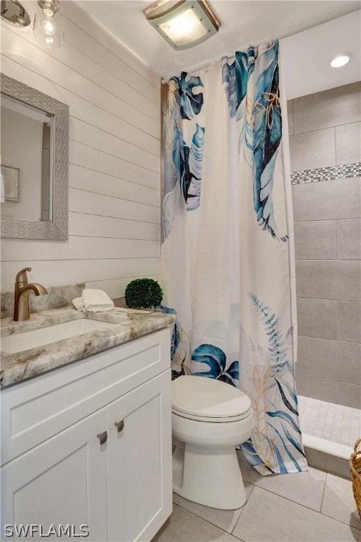 bathroom with toilet, tile patterned flooring, vanity, wood walls, and curtained shower