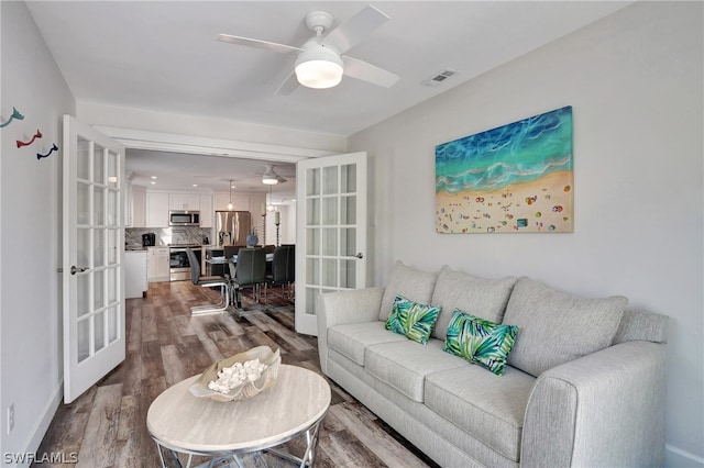 living room featuring ceiling fan, wood-type flooring, and french doors