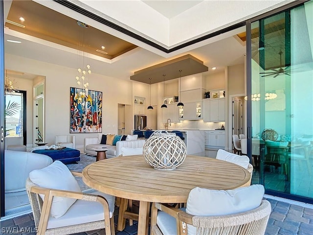 dining room with a raised ceiling, sink, and a towering ceiling