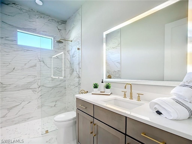 bathroom featuring a tile shower, vanity, and toilet