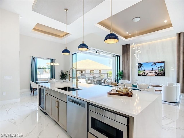 kitchen featuring dishwasher, a center island with sink, a raised ceiling, sink, and built in microwave