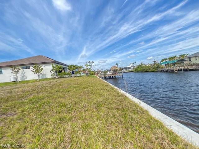 dock area with a lawn and a water view