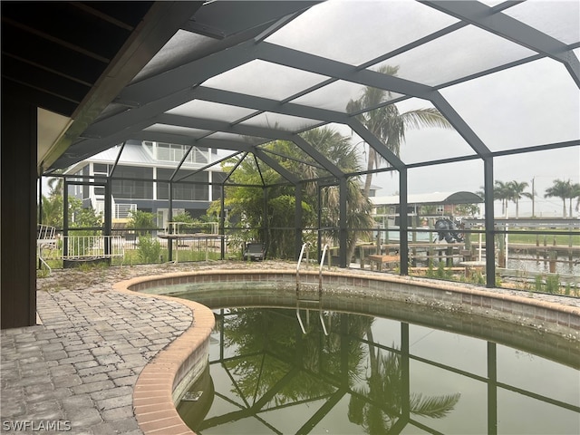 view of pool with a water view, a patio, and a lanai