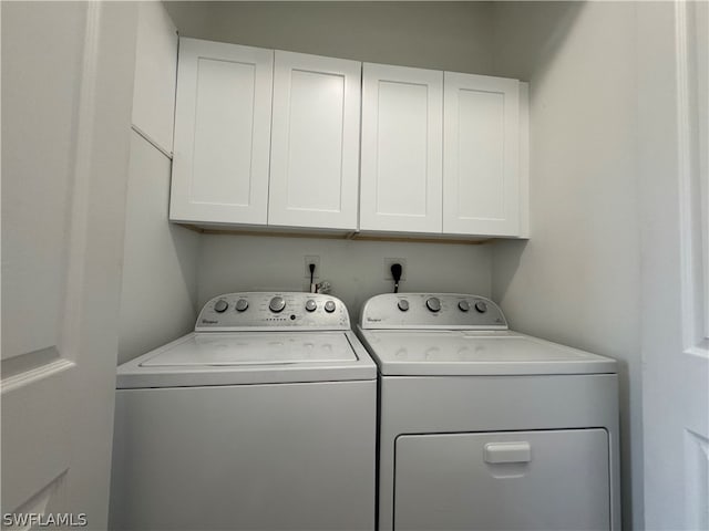 washroom featuring electric dryer hookup, washer and clothes dryer, and cabinets