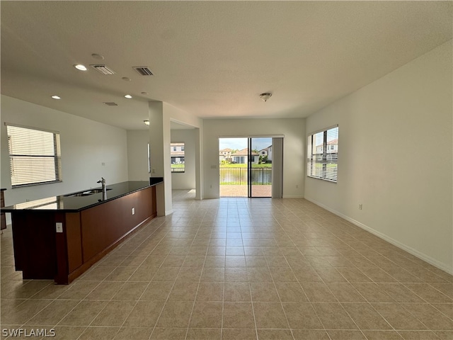 kitchen featuring sink, a kitchen island with sink, and light tile floors