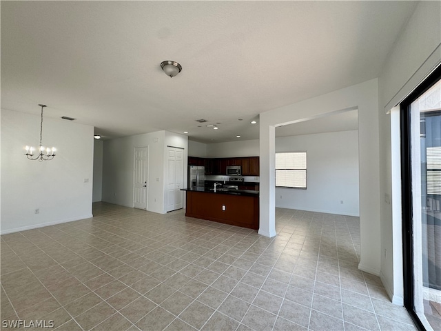 unfurnished living room with sink, light tile flooring, and an inviting chandelier