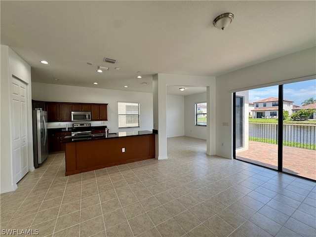 kitchen featuring appliances with stainless steel finishes, sink, light tile floors, and a kitchen island