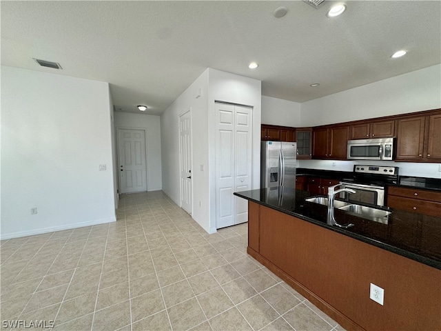 kitchen featuring appliances with stainless steel finishes, sink, dark stone countertops, and light tile floors