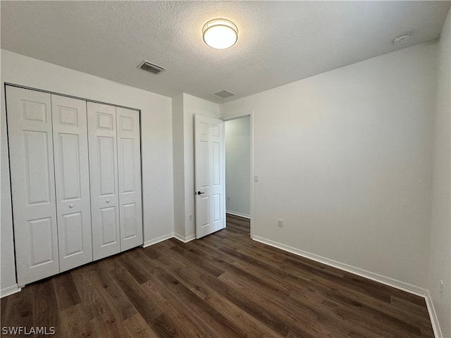 unfurnished bedroom featuring a closet, dark hardwood / wood-style flooring, and a textured ceiling